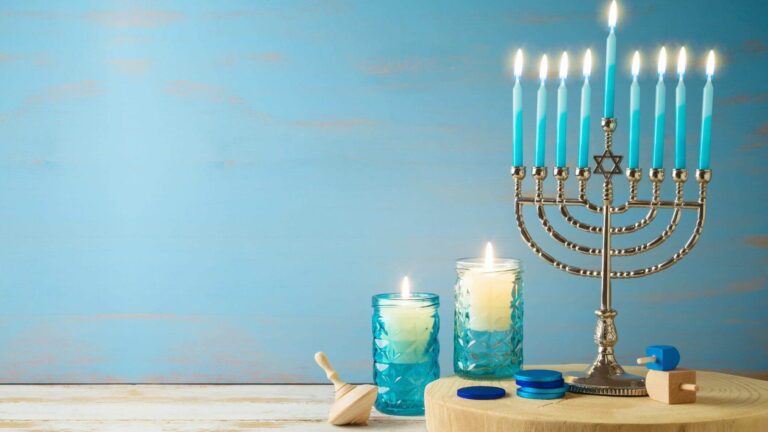 Jewish holiday Hanukkah concept with menorah, candles and dreidel on wooden table. Background for greeting card or banner